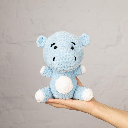 a hand holding a small blue stuffed animal