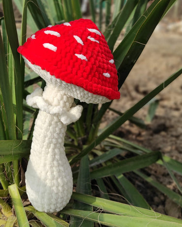 a crocheted mushroom sitting on top of a plant