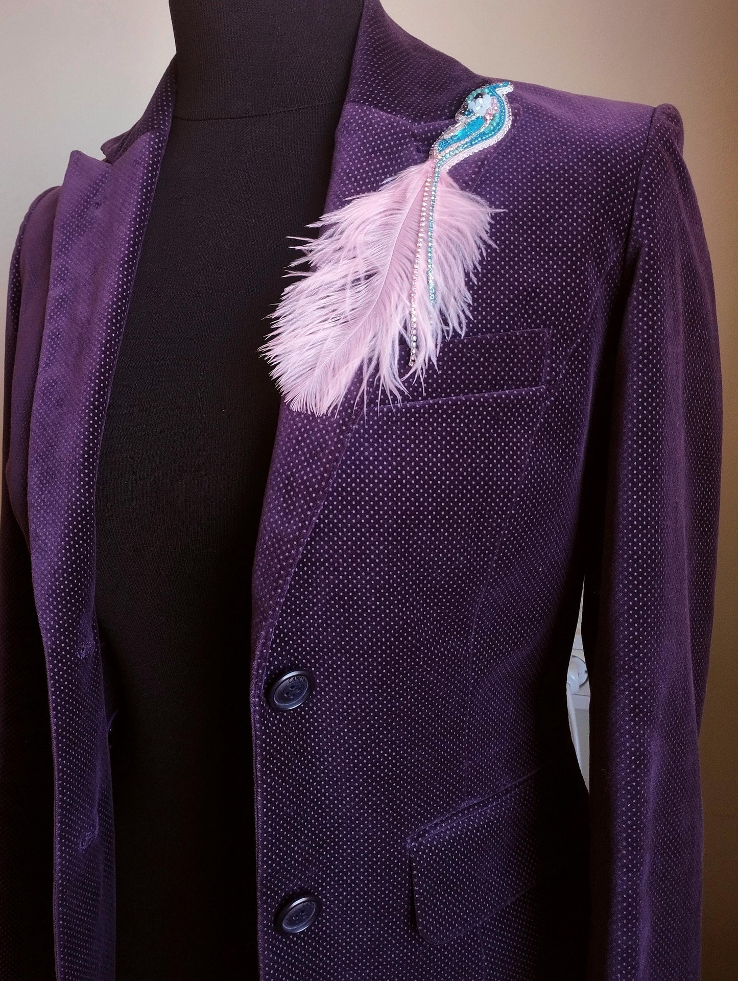 A purple velvet jacket with a feather pin on the left side.