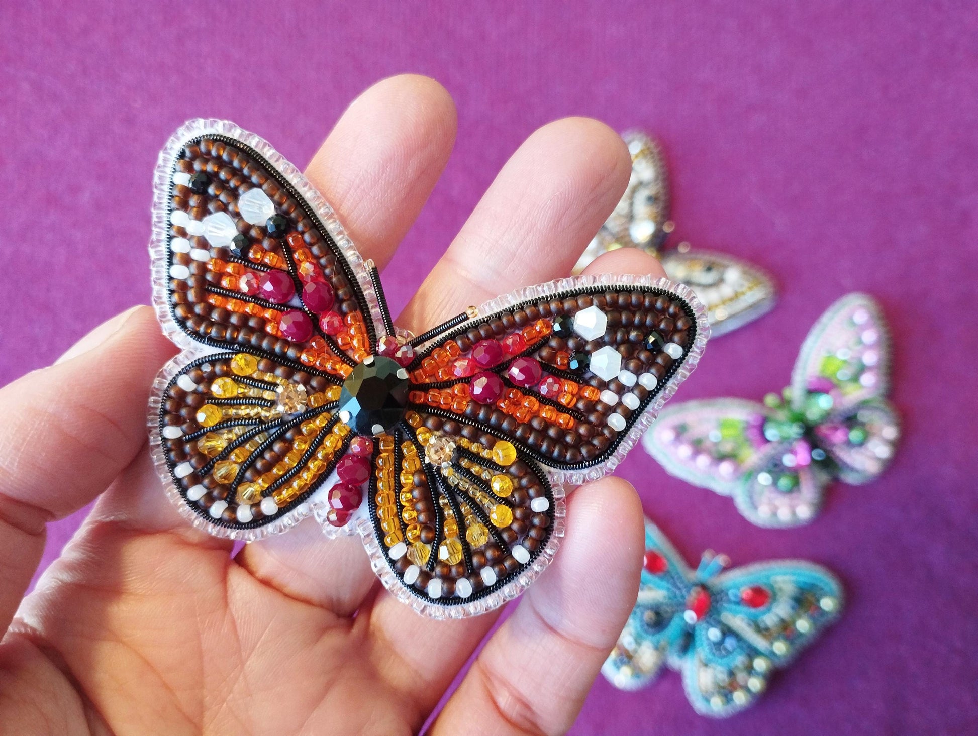 a hand holding a butterfly shaped brooch in it's palm