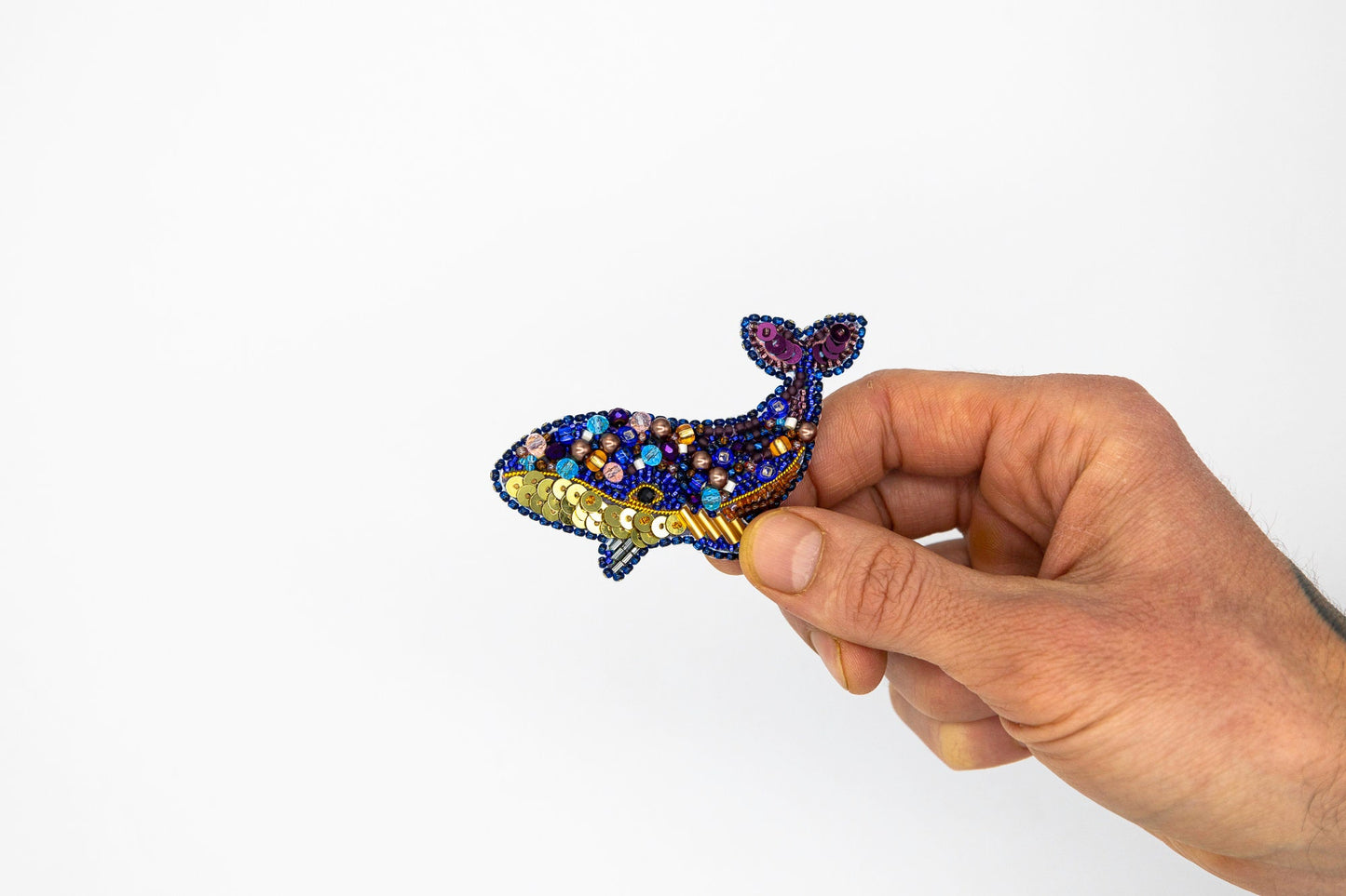 a hand holding a small blue and gold brooch