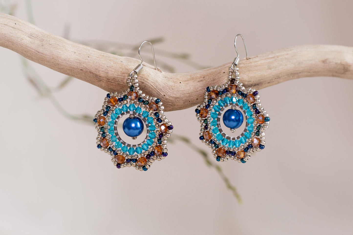 a pair of blue and orange earrings on a branch