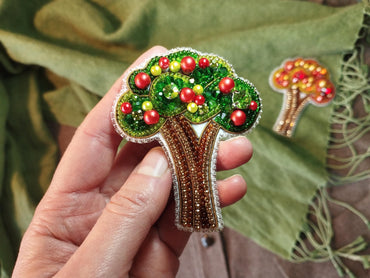 a person holding a brooch with a tree on it
