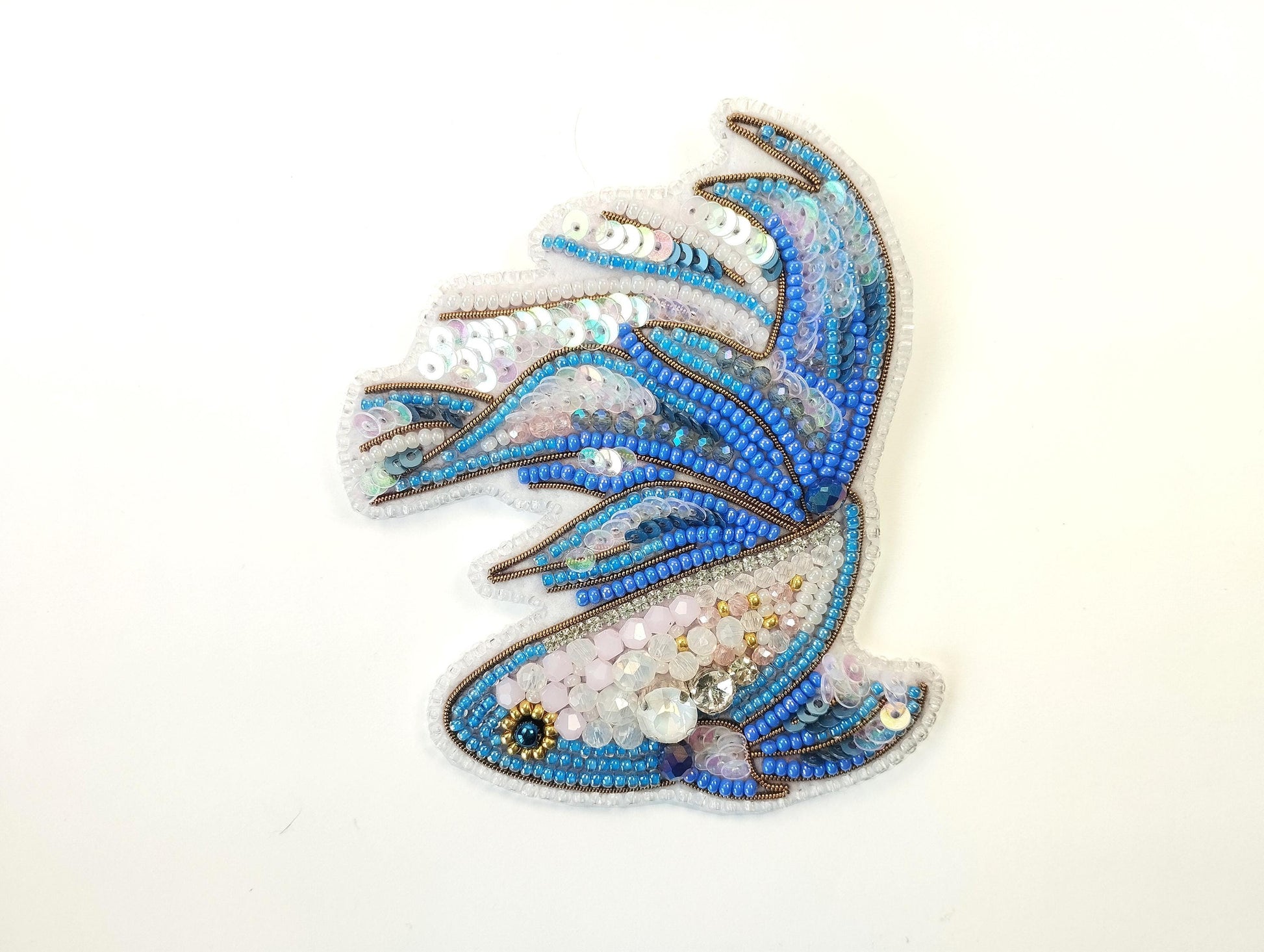 a blue and white brooch sitting on top of a white table