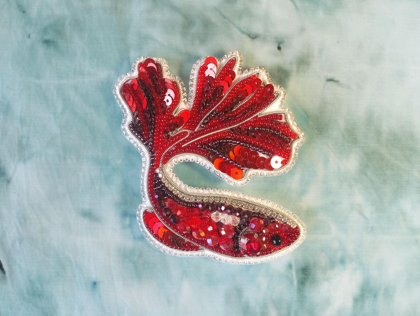 a red and white bird made out of sequins