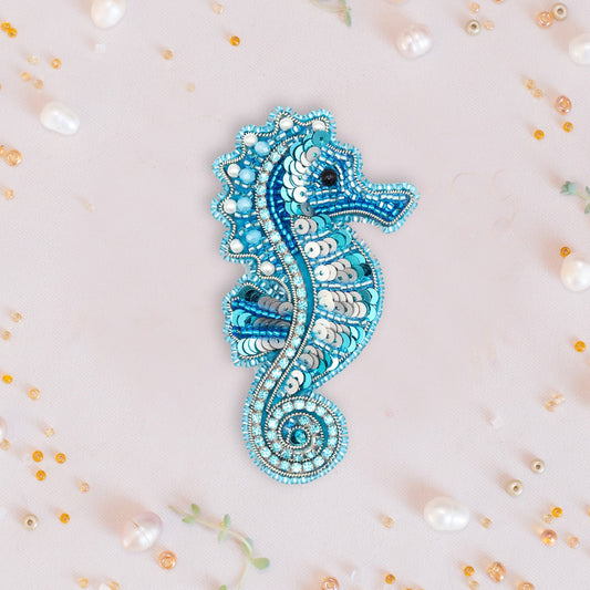 a blue seahorse brooch sitting on top of a white surface