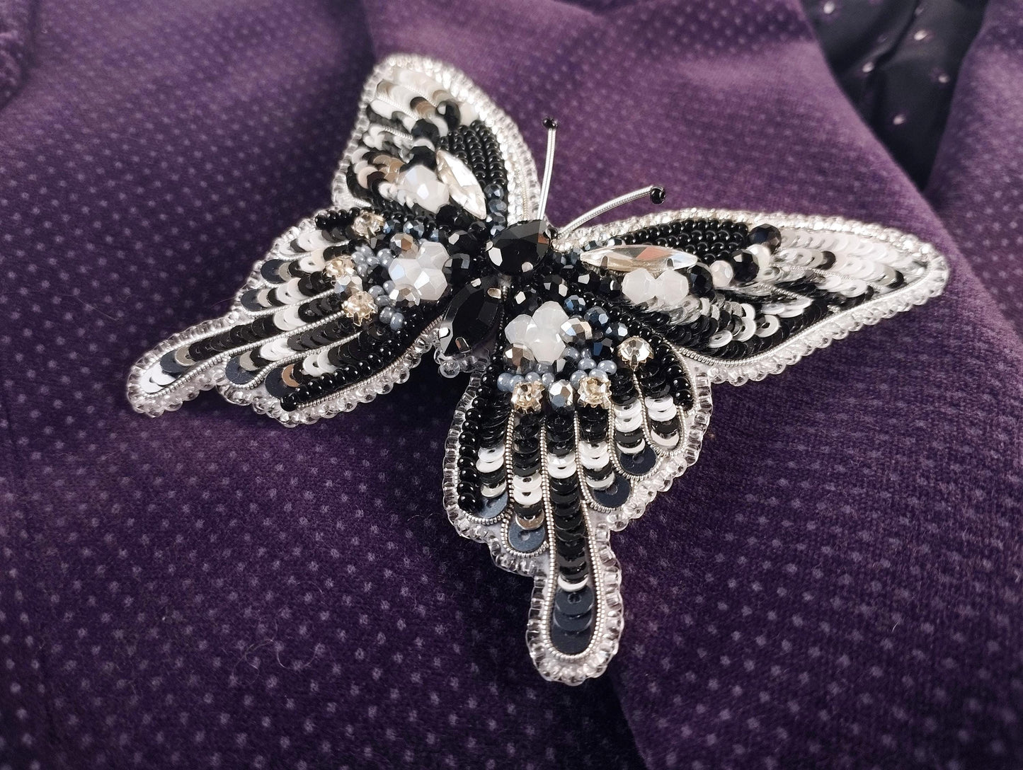 a black and white butterfly brooch sitting on a purple cloth