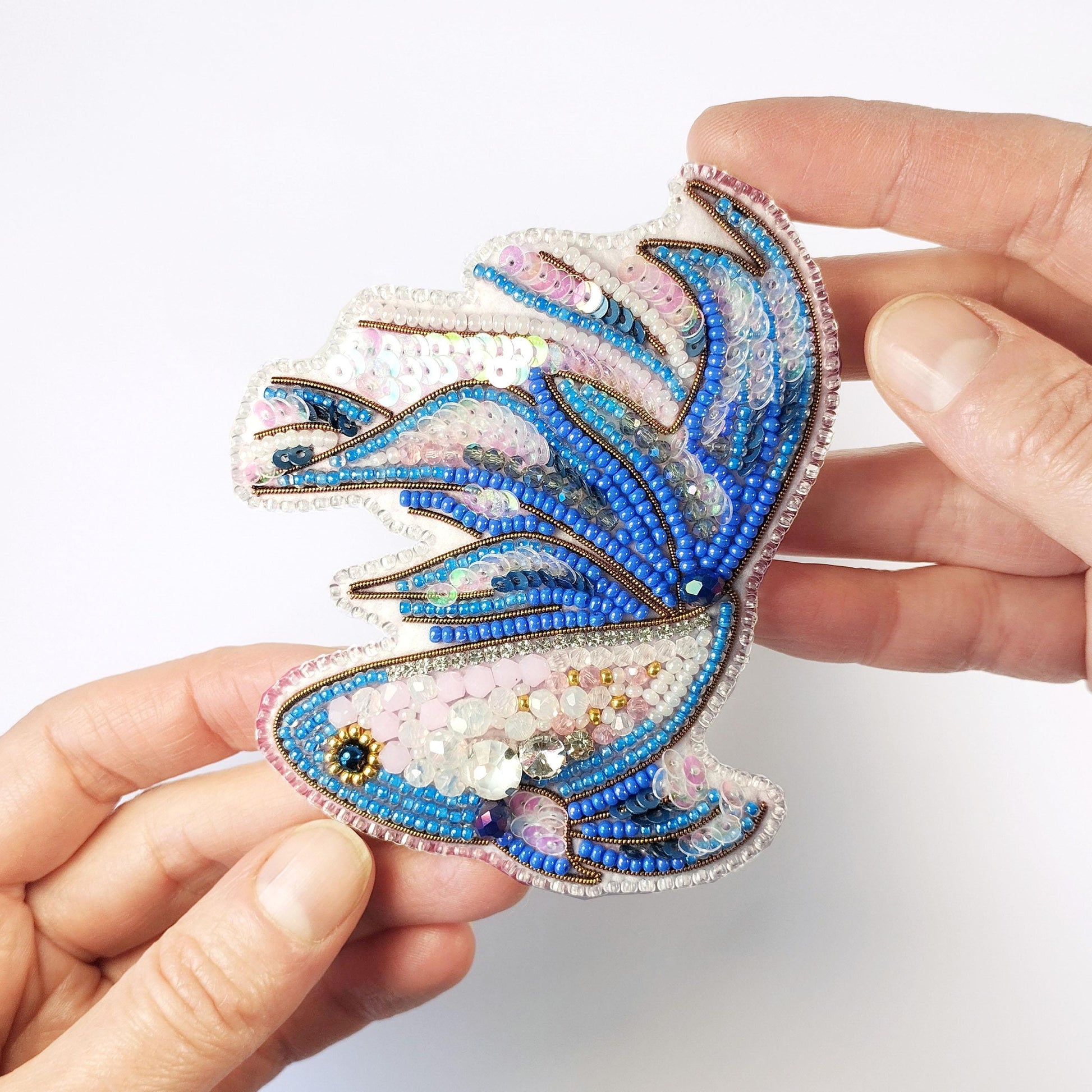 a hand holding a blue and white brooch