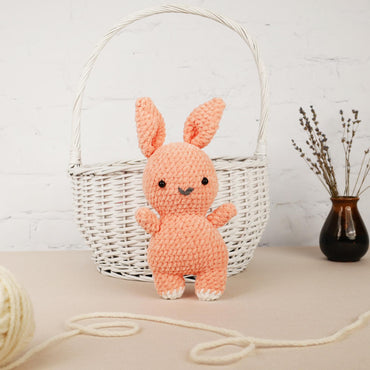a crocheted bunny sitting in front of a basket