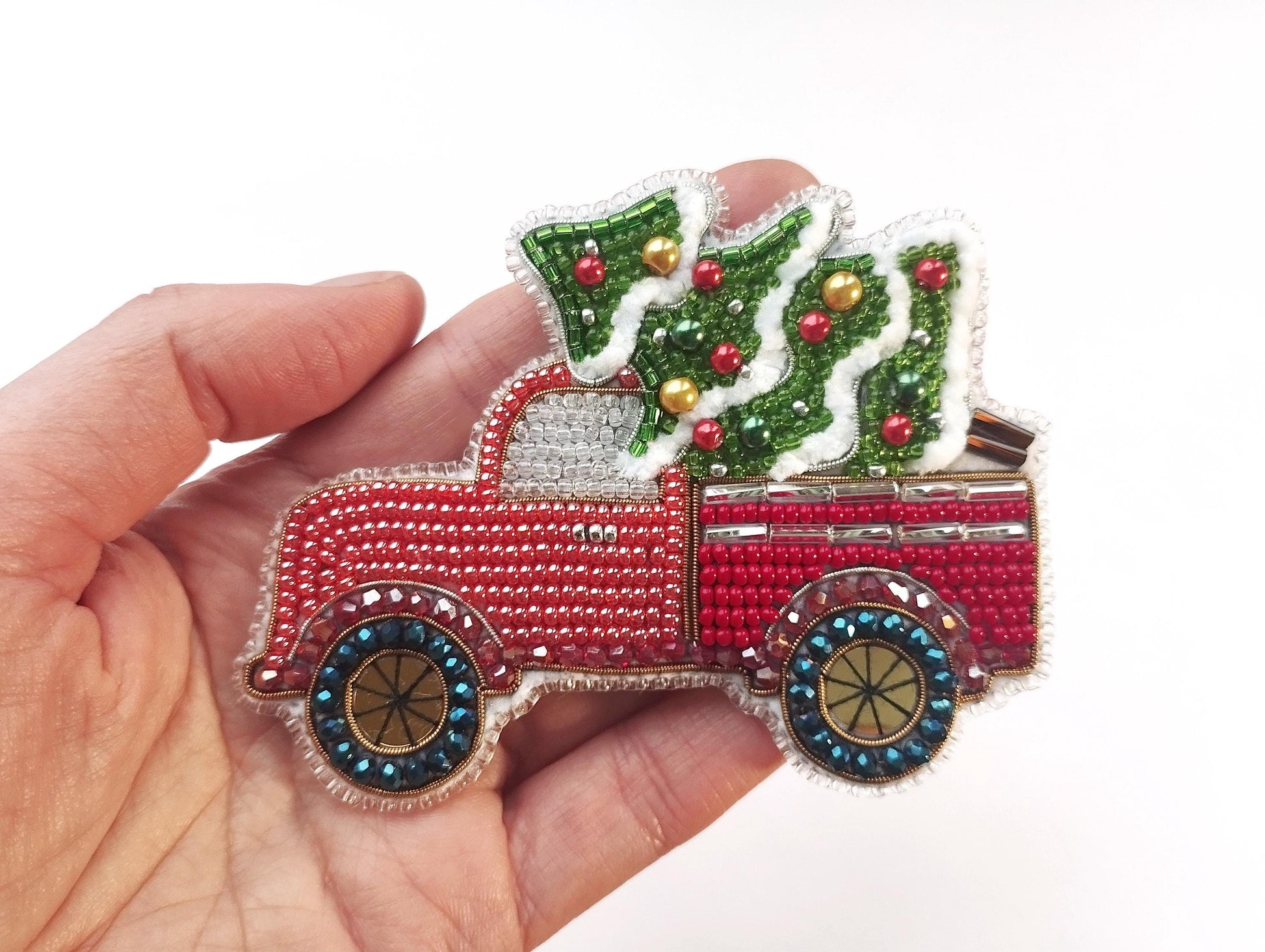 a hand holding a small christmas truck ornament