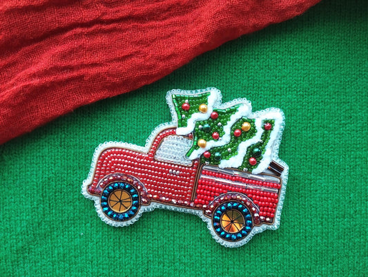 A red truck decorated with Christmas ornaments and a Christmas tree is displayed on a green background.
