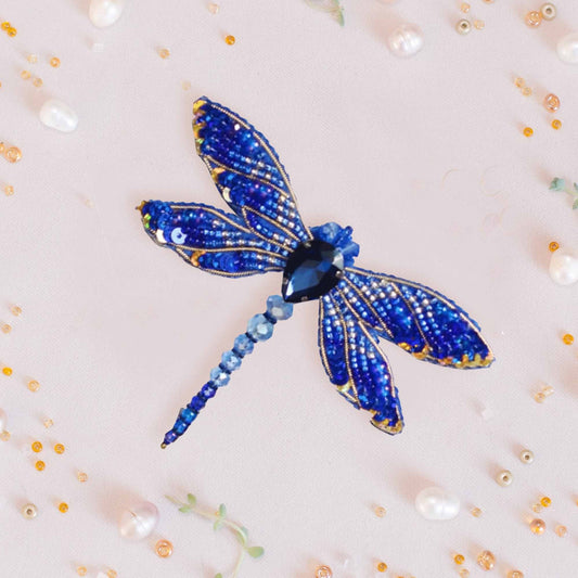 a blue dragonfly brooch sitting on top of a white surface