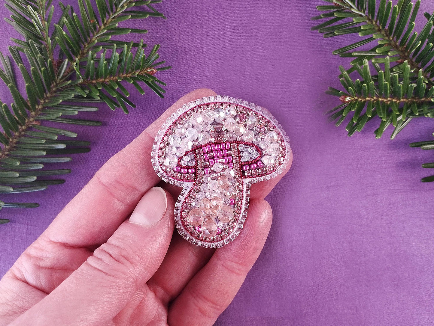 a hand holding a pink and white brooch