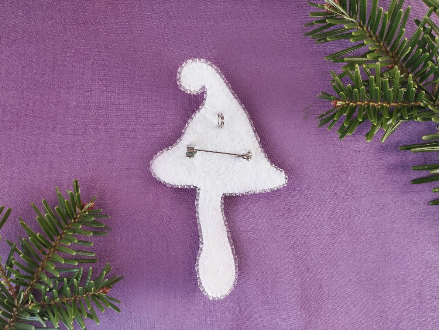 a white brooch sitting on top of a purple surface