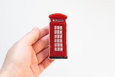 a hand holding a needle - embroidered phone booth