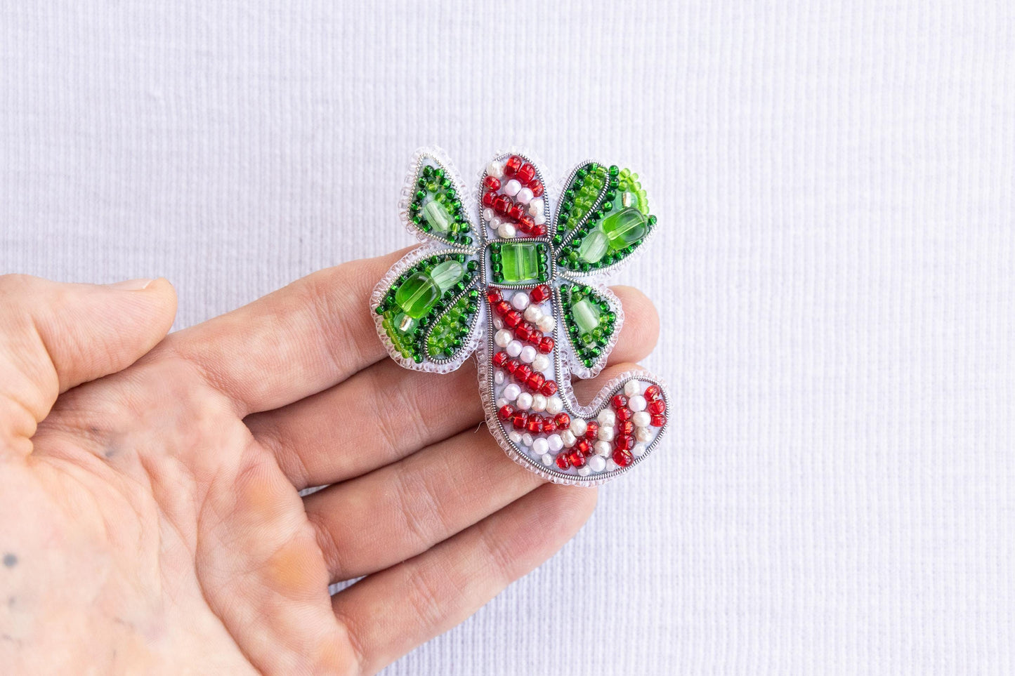 a person is holding a brooch with candy canes on it