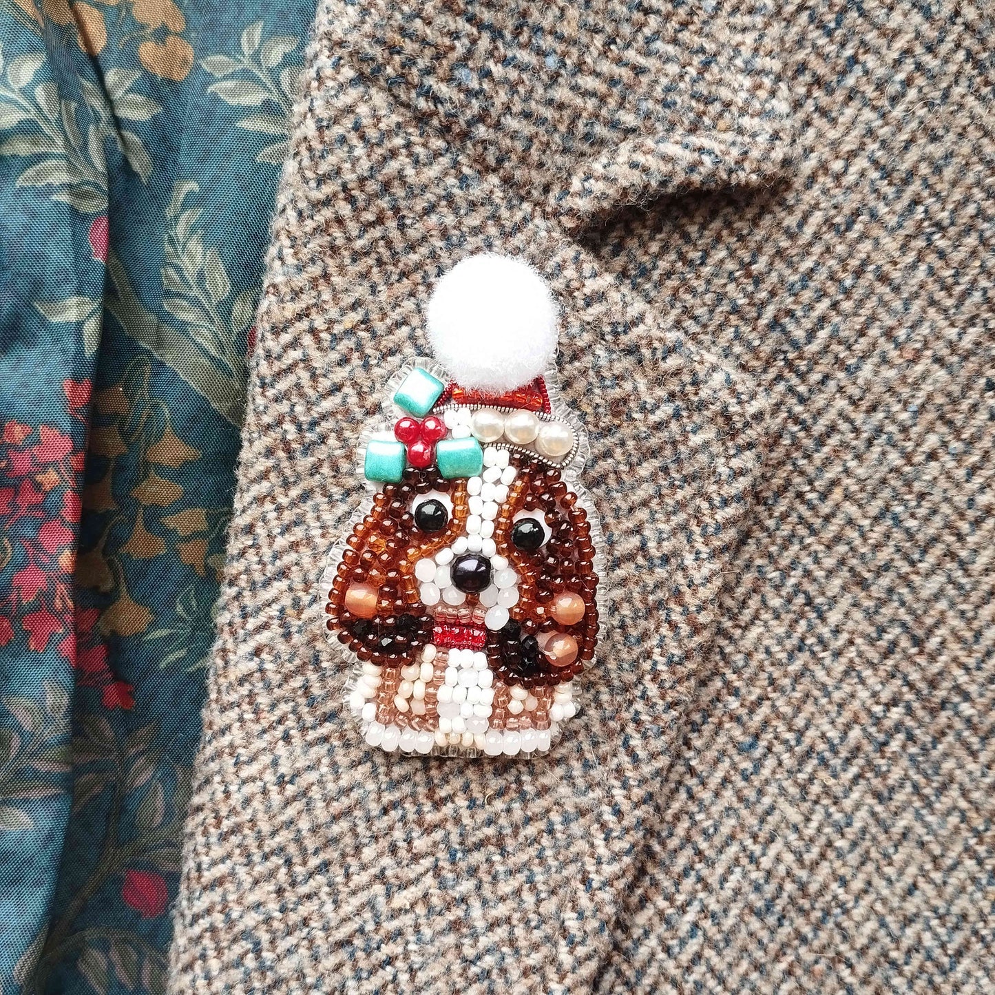 A close-up of a beaded dog brooch on a tweed jacket.
