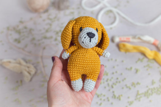 a hand holding a small crocheted dog