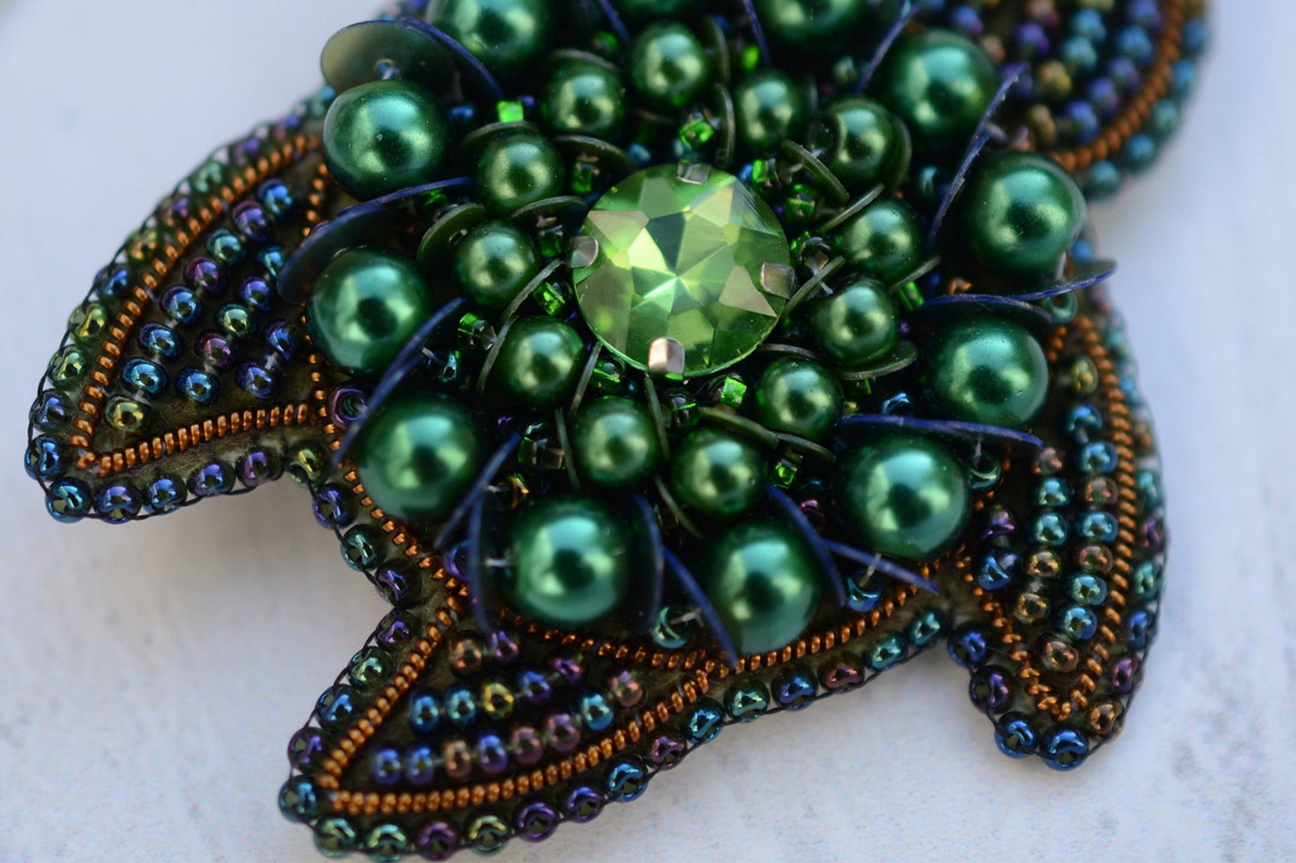 a close up of a brooch on a white surface