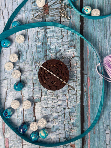 a piece of wood that has some knitting needles and beads on it