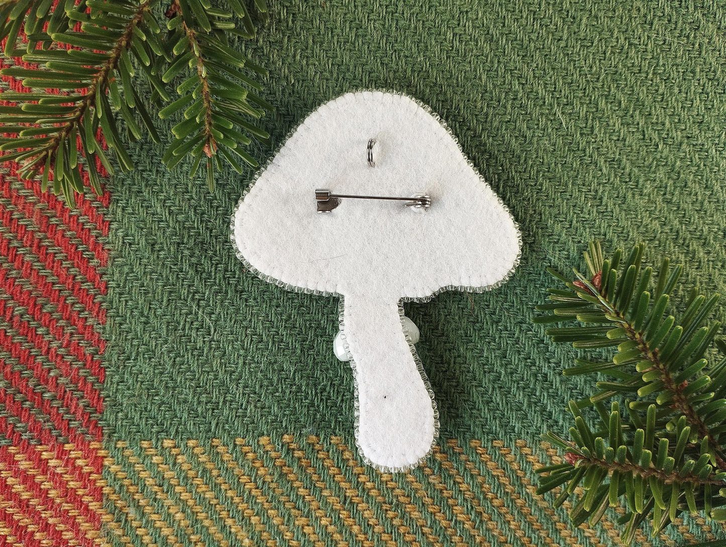 a white clock sitting on top of a table next to a pine tree