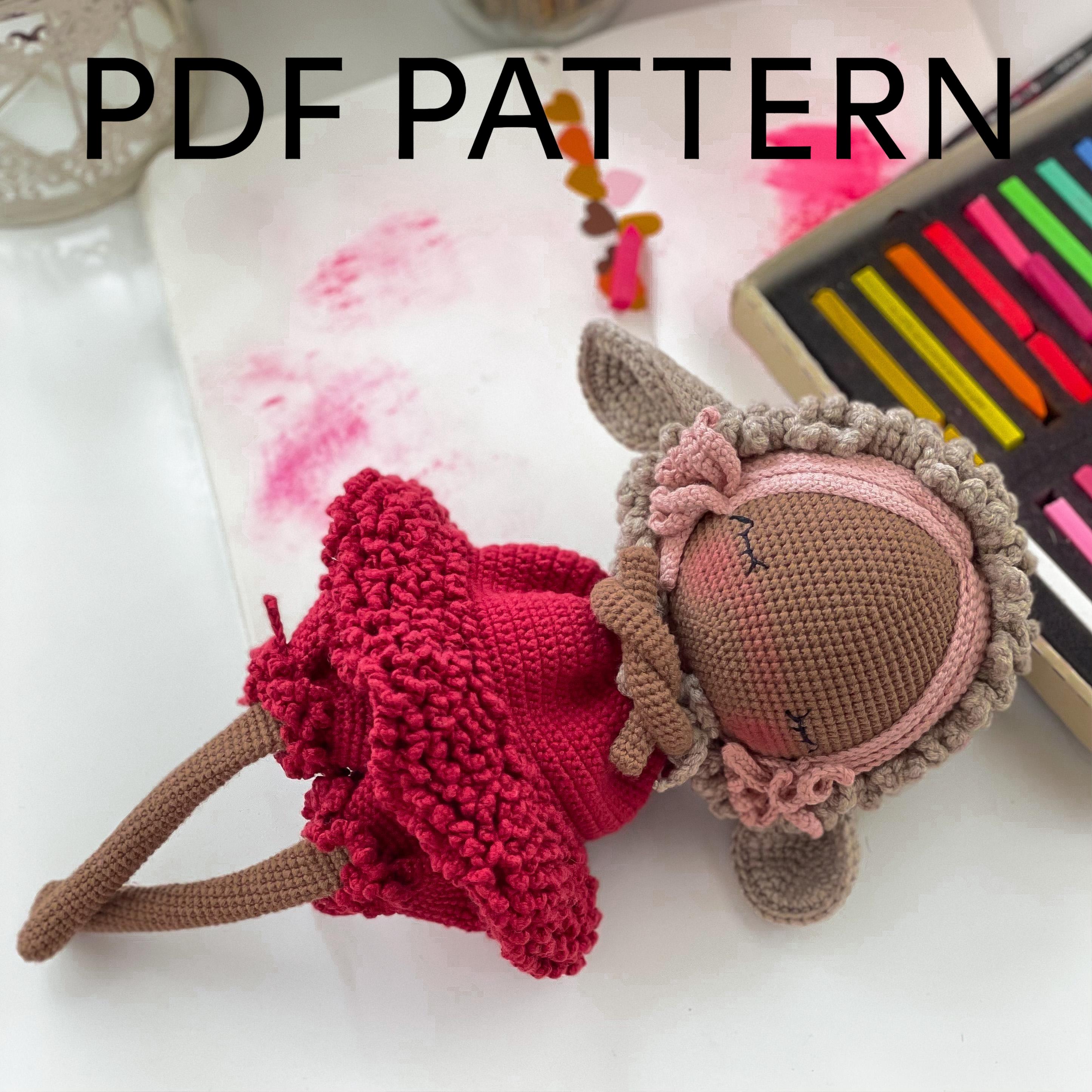 a knitted doll laying on top of a table next to a crayon