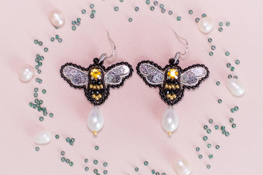 a pair of earrings with a bee on it