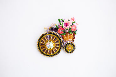 a beaded brooch with flowers in a carriage