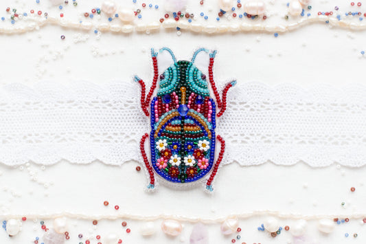 a beaded bug is sitting on a white surface