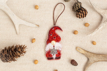 a red ornament resembling a gnome, surrounded by various natural elements such as pine cones, antlers, and small pinecones.