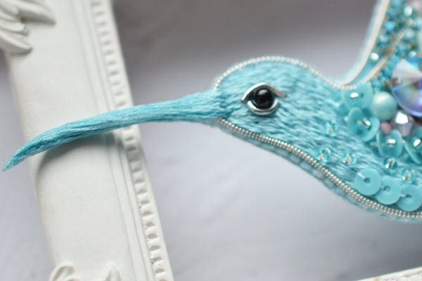 a blue bird with pearls and pearls on it's head