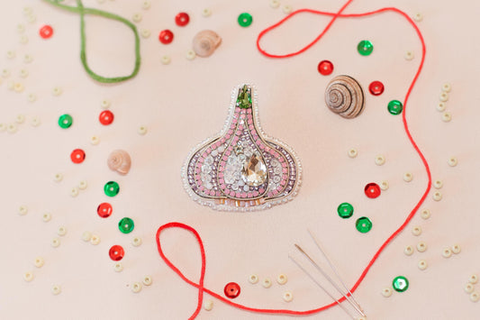 a close-up view of a decorative piece, possibly a brooch or pendant, surrounded by various craft supplies such as beads, strings, and buttons.