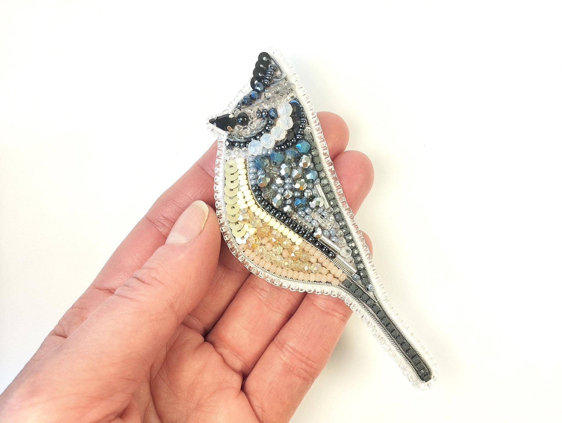 a hand holding a small beaded bird