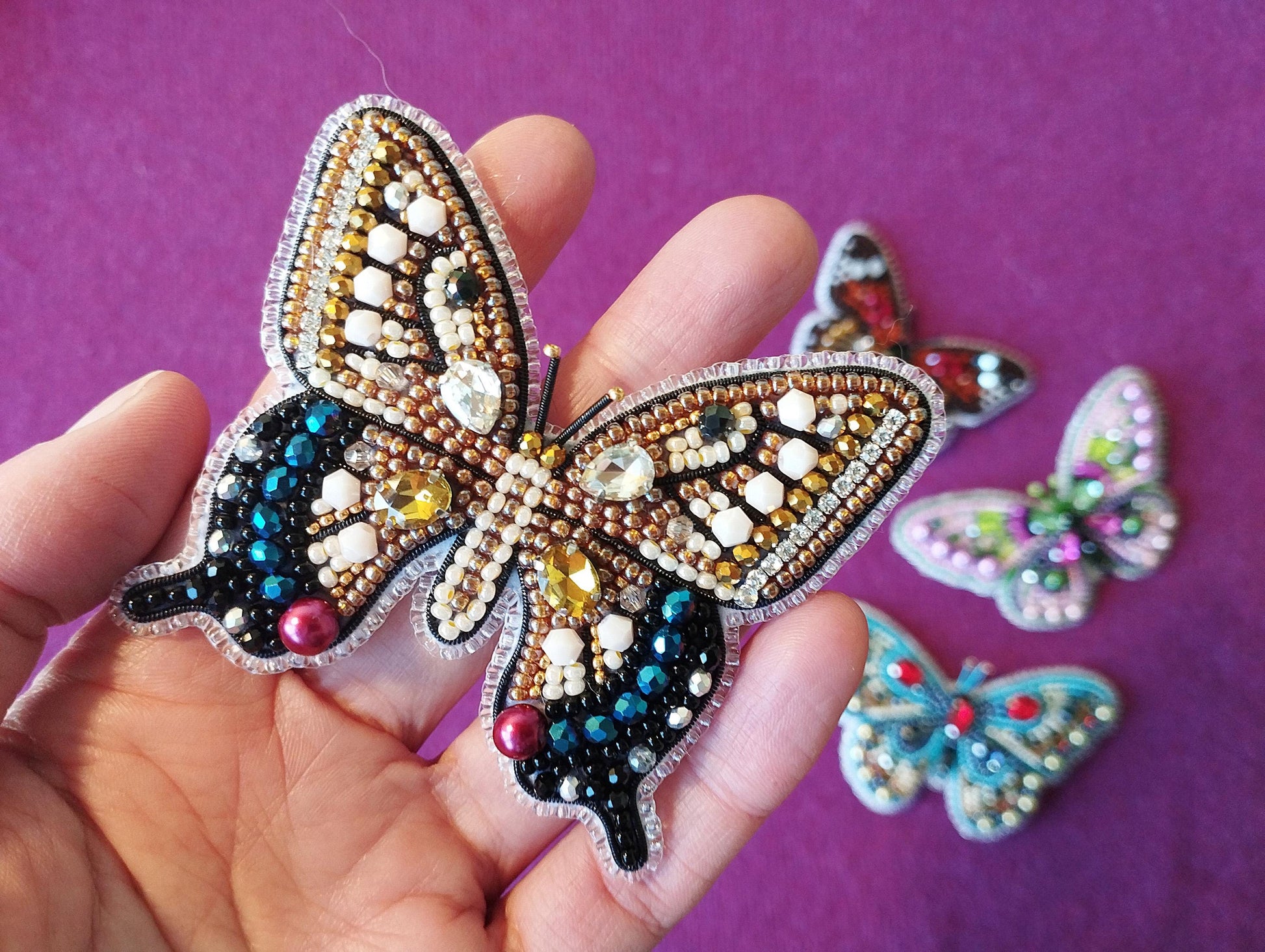 a person holding a butterfly brooch in their hand