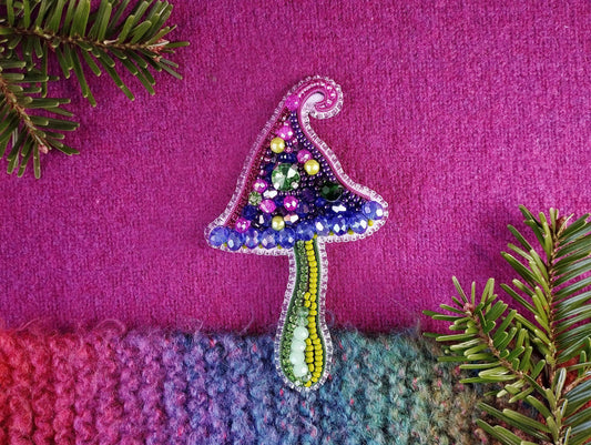 a knitted christmas tree ornament sitting on top of a purple blanket