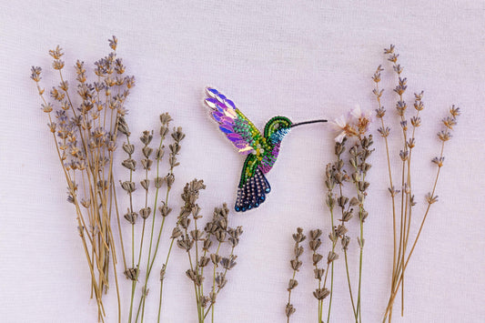 a hummingbird flying over a bunch of lavender flowers