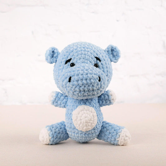 a blue crocheted stuffed animal sitting on a table