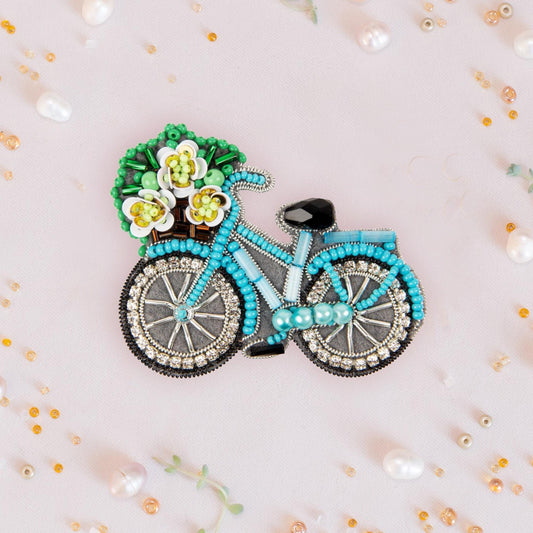 a brooch with a bicycle and flowers on it