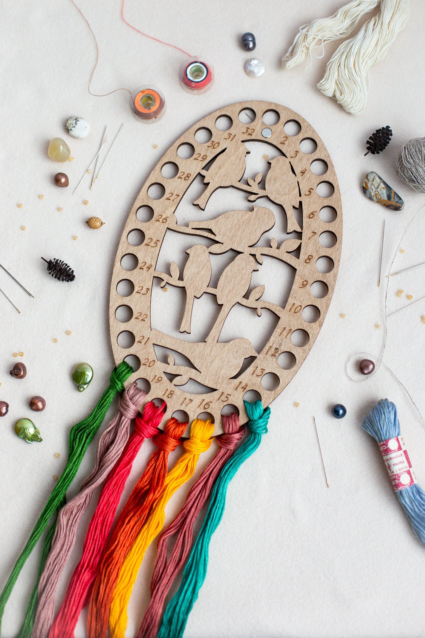 a wooden cutout of a deer surrounded by thread and beads