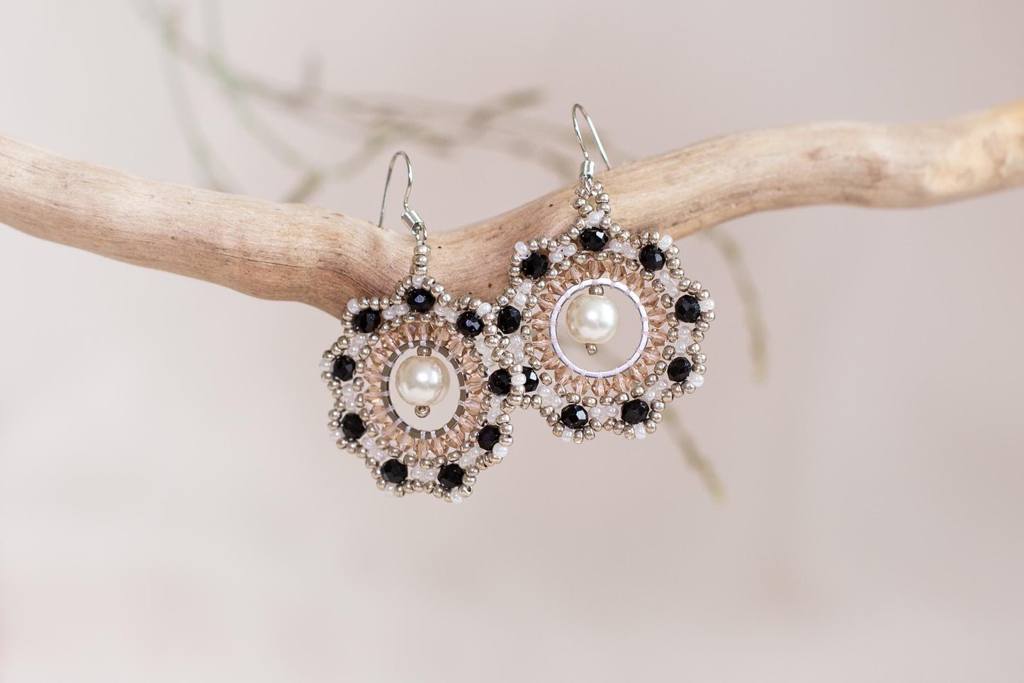 a pair of black and white earrings on a branch
