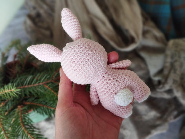 a hand holding a pink crocheted stuffed animal