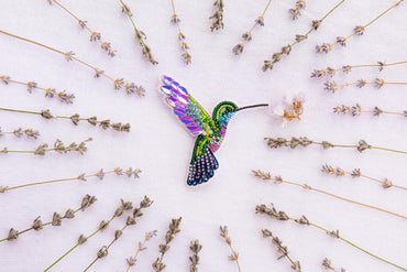 a colorful hummingbird flying over a field of flowers