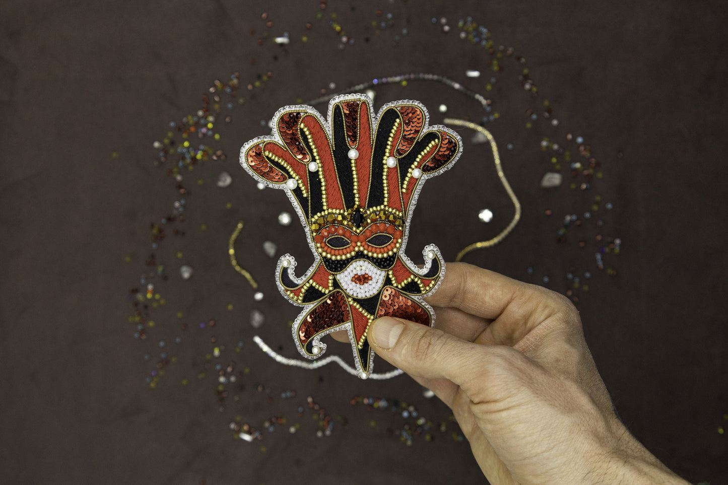 a hand is holding a mask with beads on it