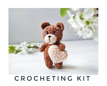 a crocheted teddy bear holding a heart