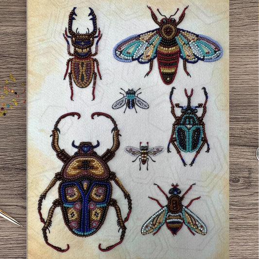 a collection of six intricately designed insects, including a large beetle, a colorful butterfly, and several smaller insects, all crafted from beads.