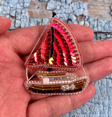a hand holding a miniature model of a sailboat