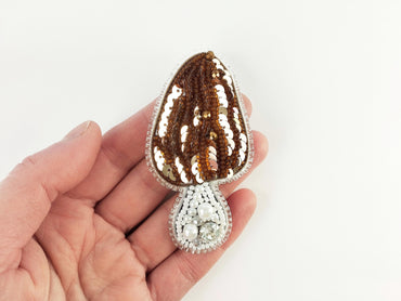 a hand holding a brown and white brooch