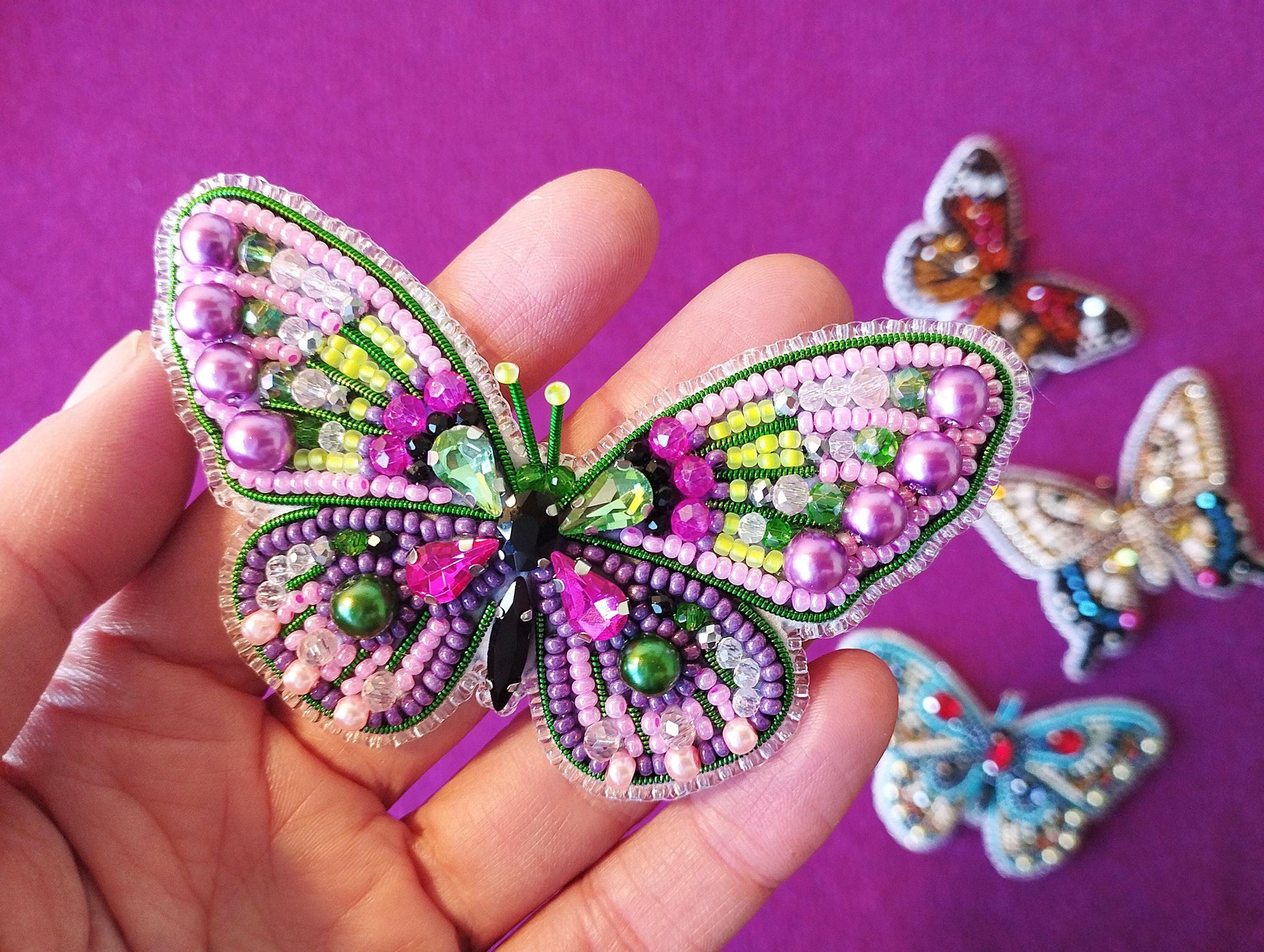 a hand is holding a small butterfly brooch