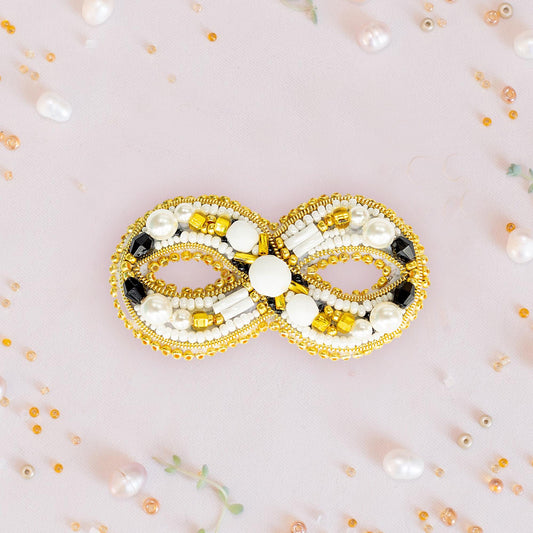 a gold and white beaded brooch sitting on a table