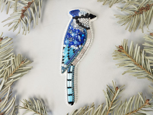 a blue bird ornament sitting on top of a pine tree